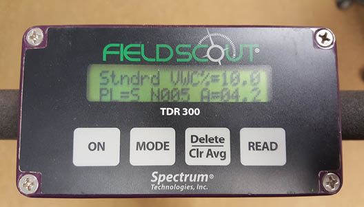 A Spectrum Technologies TDW 300 screen displaying the output of an instantaneous volumetric water content reading above four buttons labelled ON, MODE, Delete/Clr Avg, and READ.