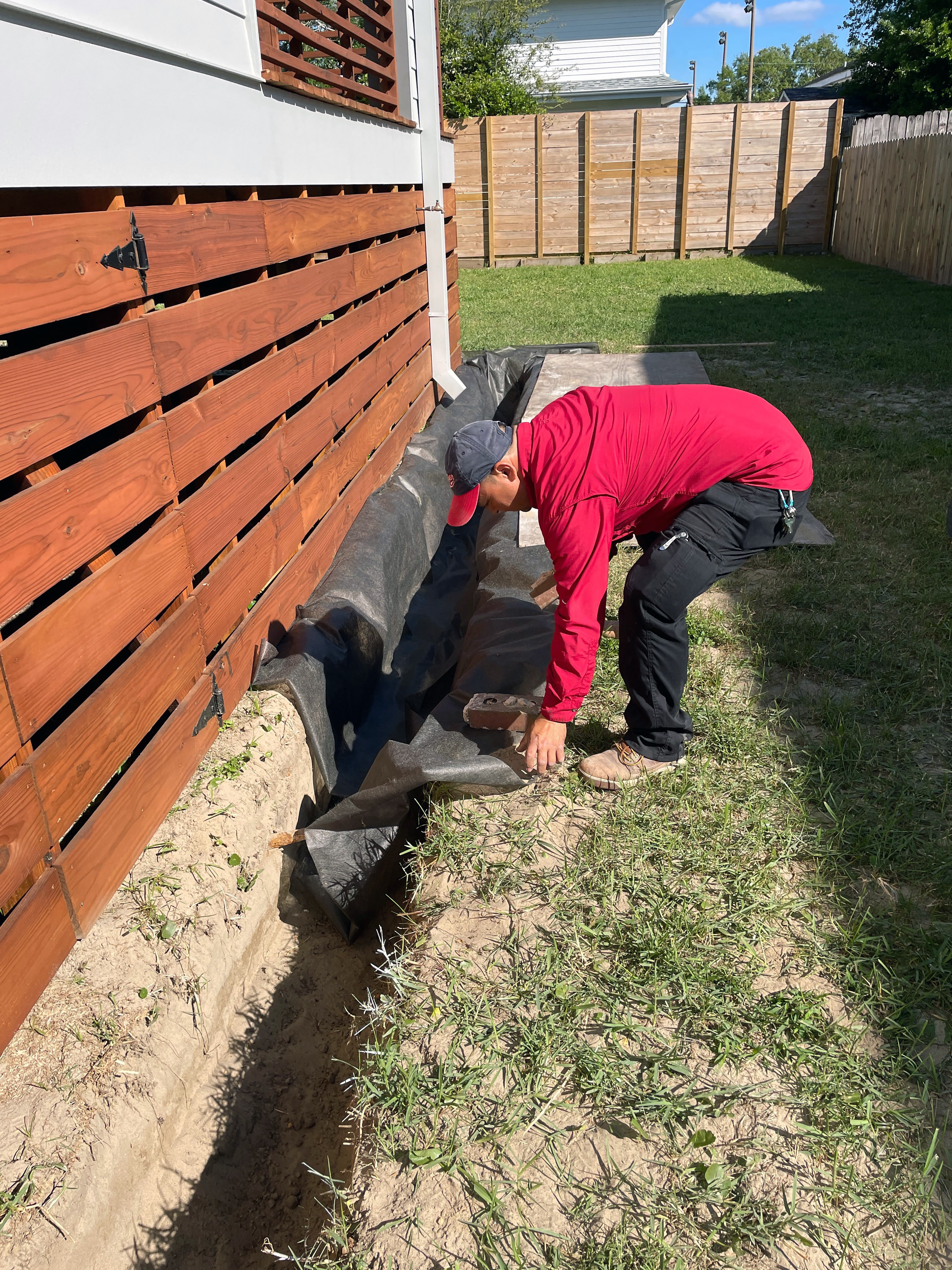 A man bends down near a trench.