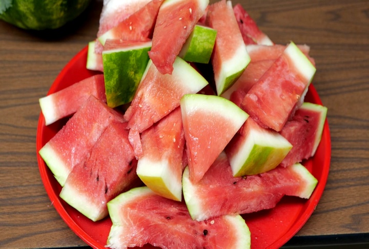 A red plate displaying cut up watermelon.