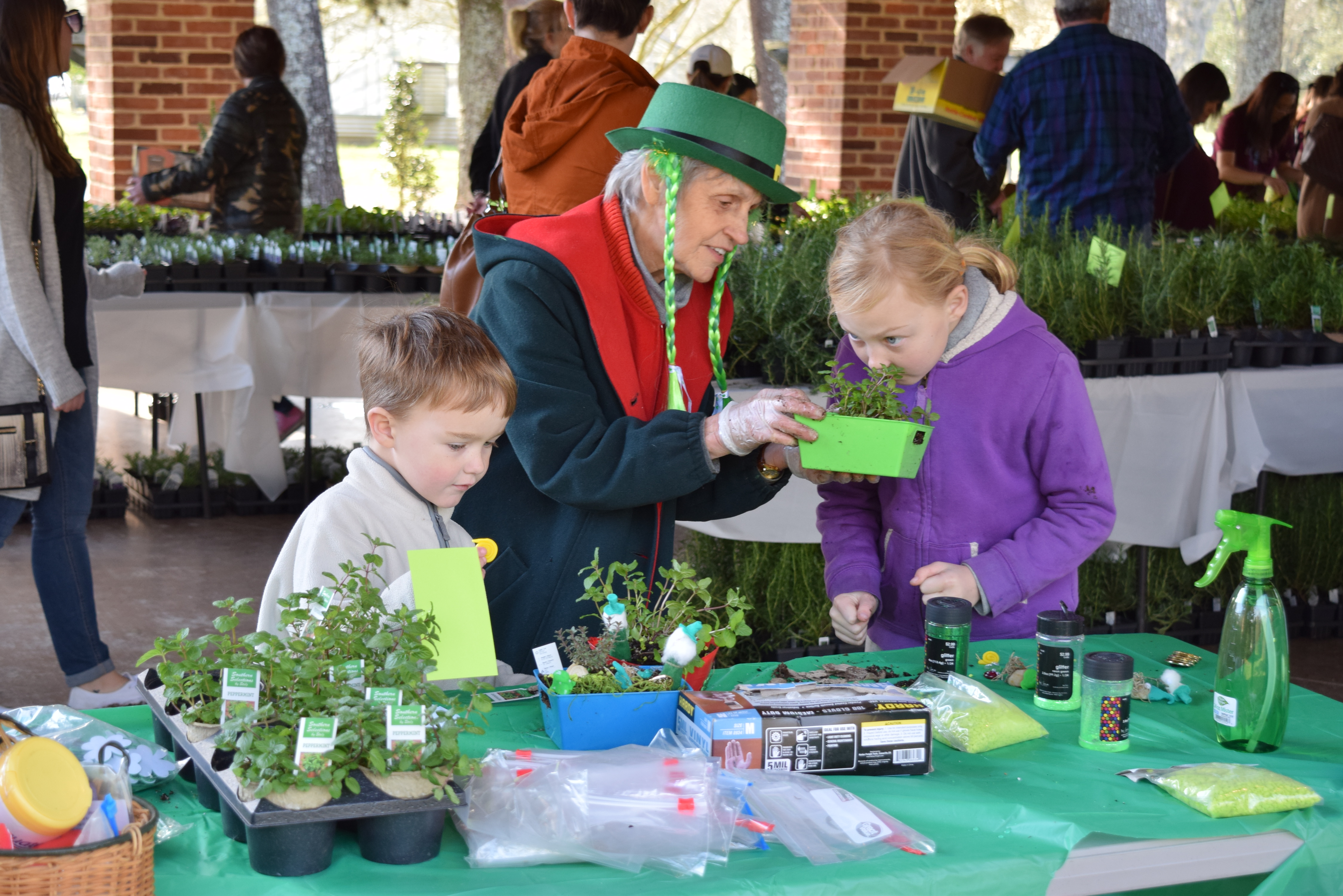 Visitors at the herb plant sale with herbs displayed on a table.