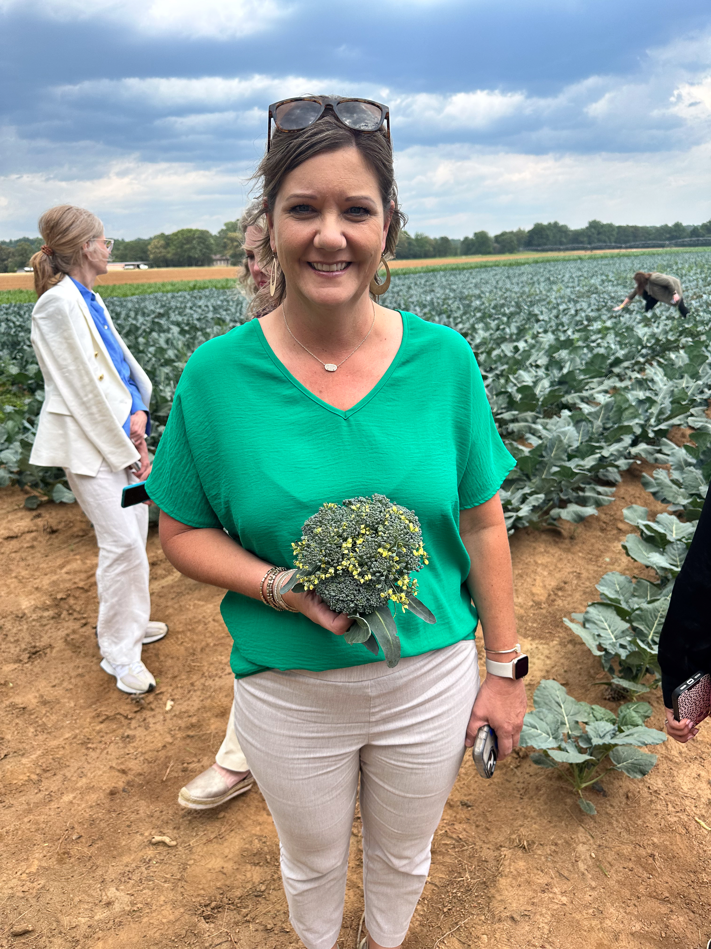 Renee Naquin showing off a head of broccoli starting to flower. 