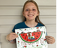 A young girl poses with a painting of a watermelon. 