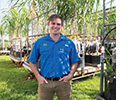 A man puts his hands in his pockets and poses in front of plants on a cart.