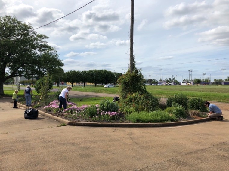 Five individuals working to maintain Louisiana native plant bed at a research station.