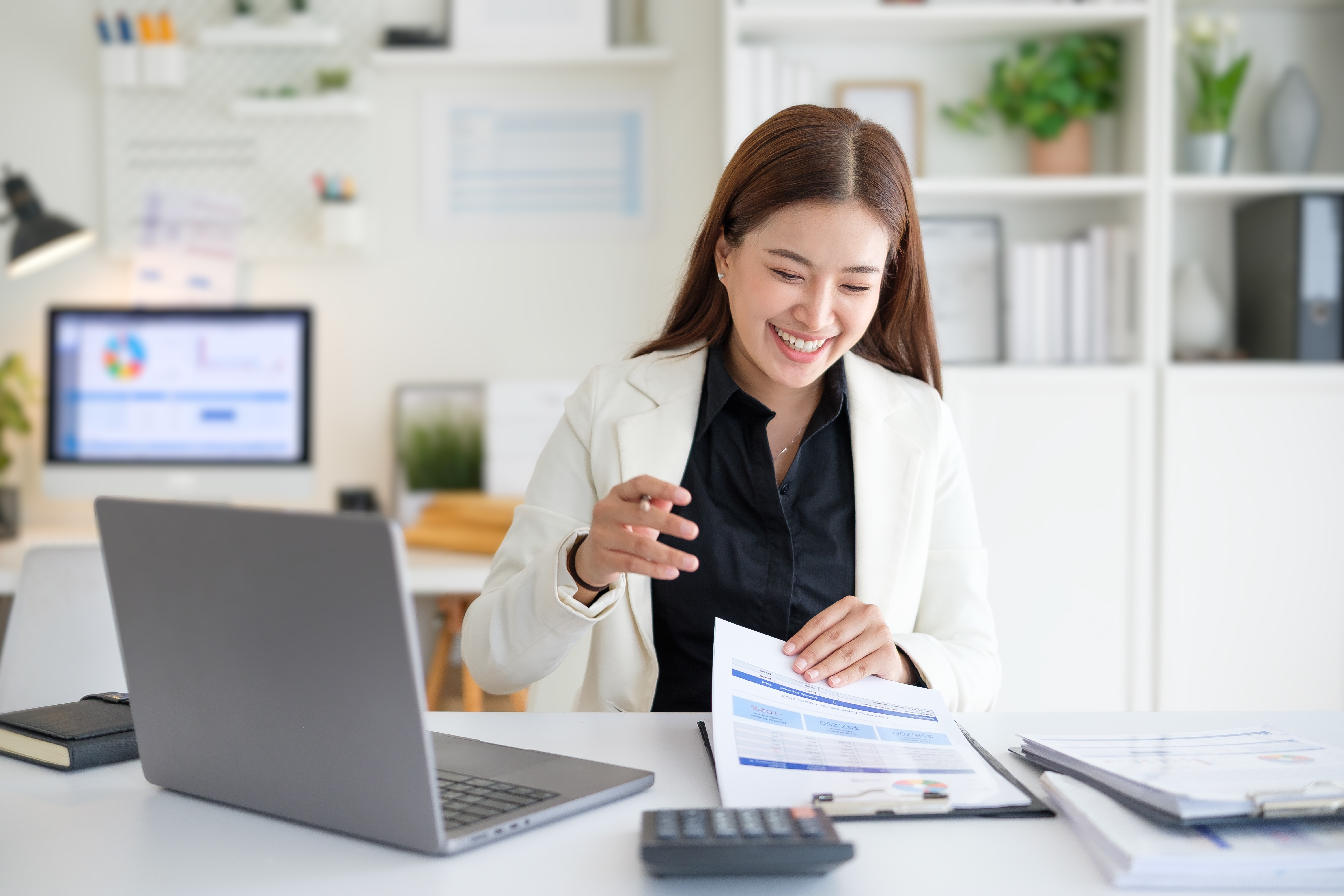 Woman looking at papers next to a laptop.