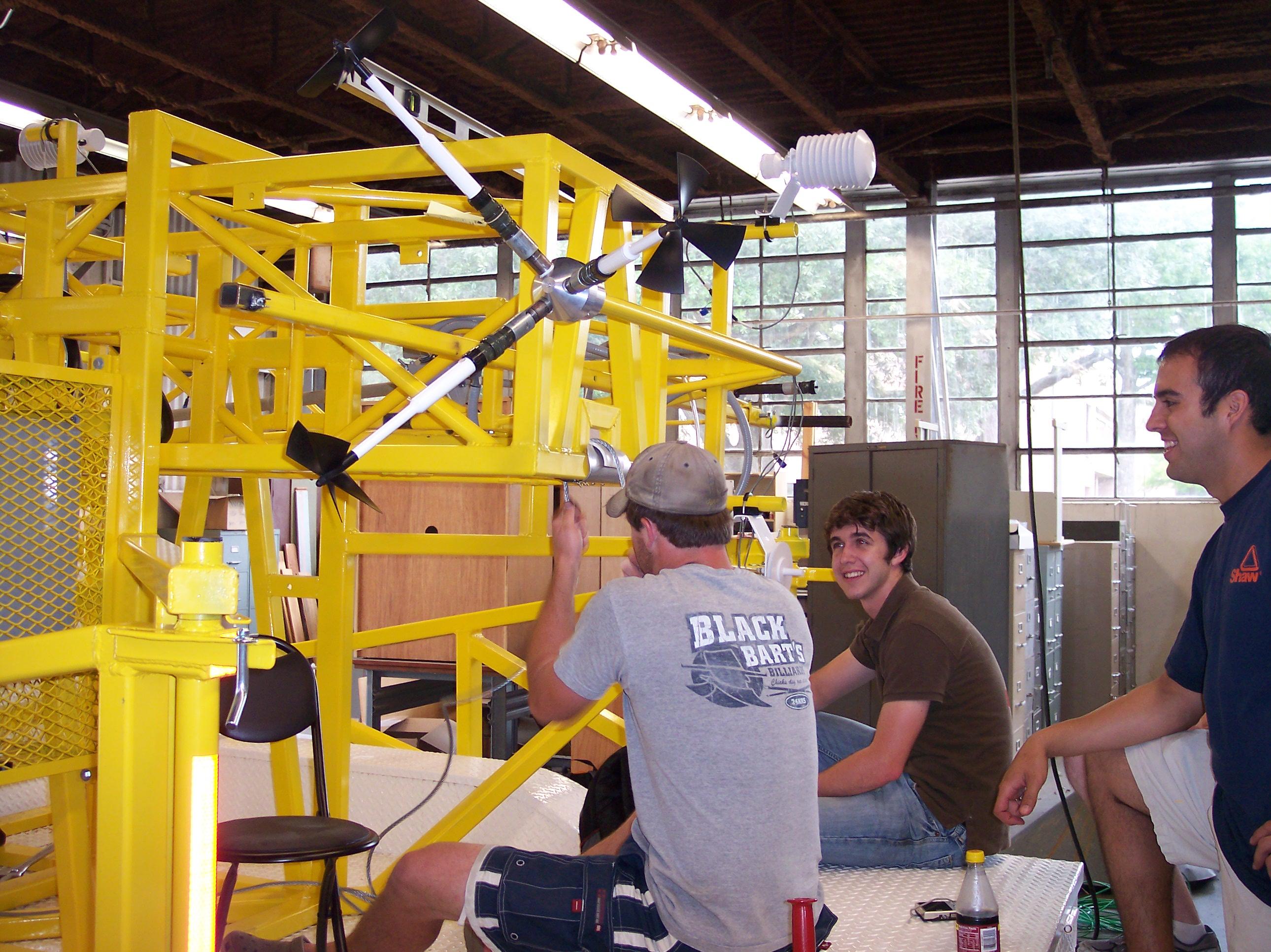 Team members adjust winch cable used to lift monitoring station.
