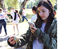 A girl uses a smartphone to take a photo of a shell in her hand.