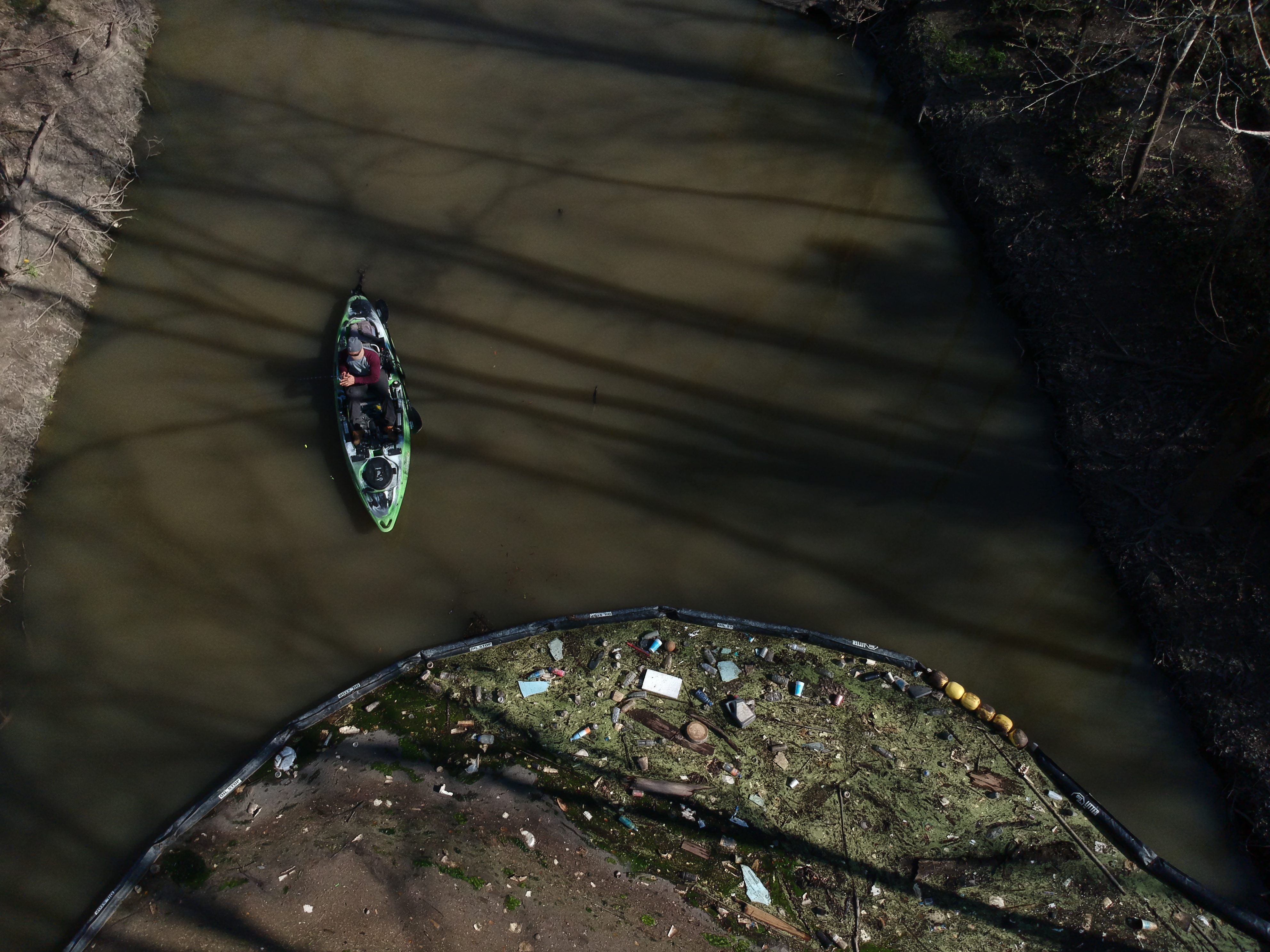 Aerial photo of a boom trapping litter in a bayou.