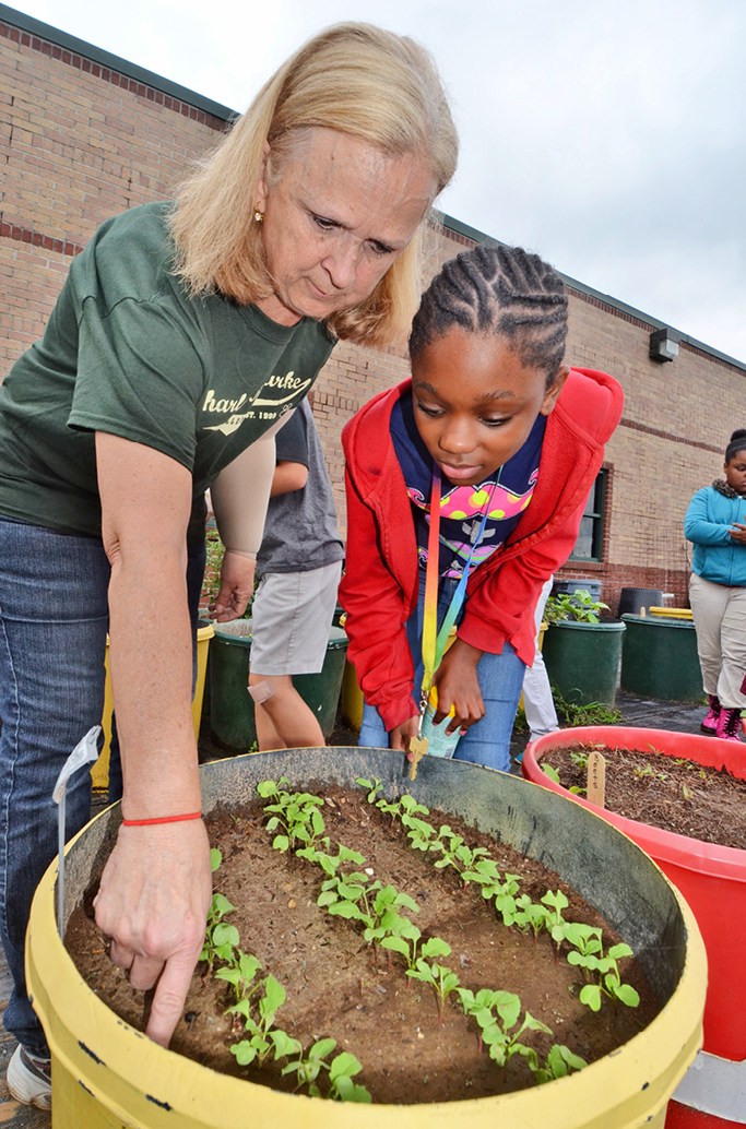 Teacher Judy Morgan shows one of her students a weed